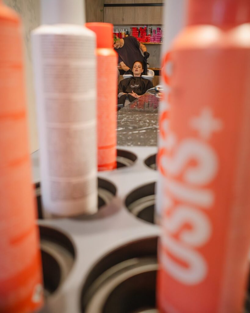 Productos OSiS de Schwarzkopf Professional en NØIR Salón, con una clienta en el lavacabezas al fondo